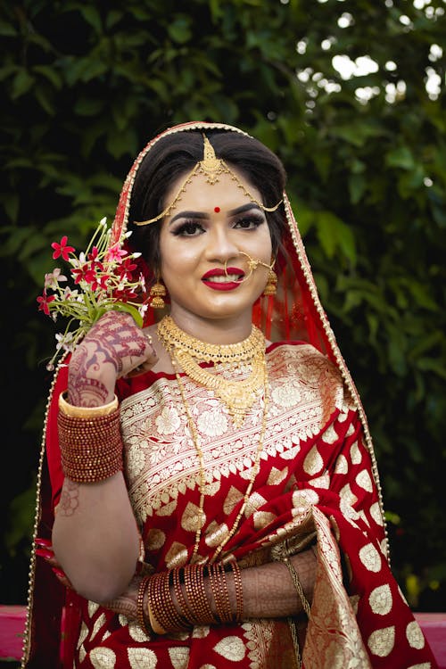 Woman in Red Sari Holding a Handful of Flowers