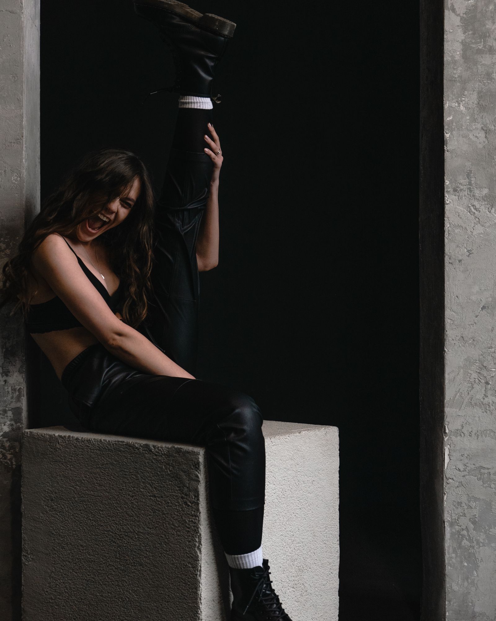 Woman in black leather pants seated on a concrete ledge
