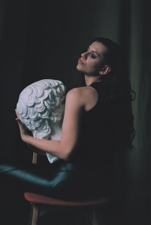 A Woman Pouting while Holding a Head Bust