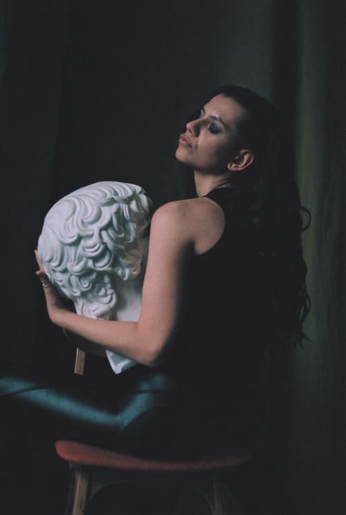 Free A dramatic portrait of a woman holding a classical sculpture, embodying elegance and mystery. Stock Photo