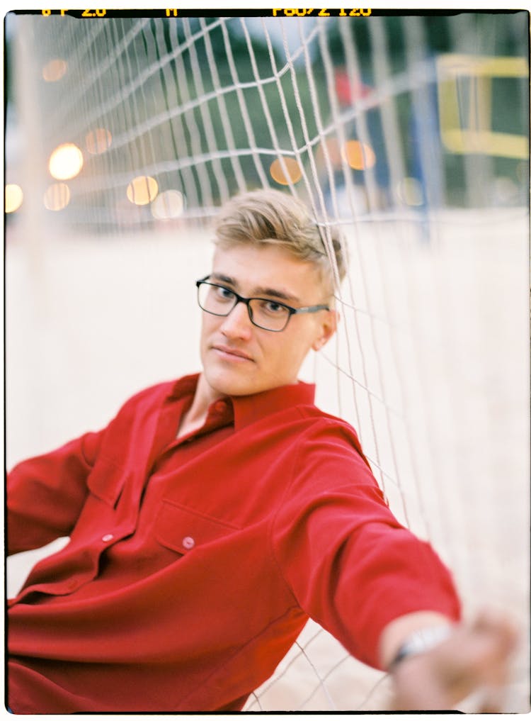 Man In Red Dress Shirt Leaning On A Net