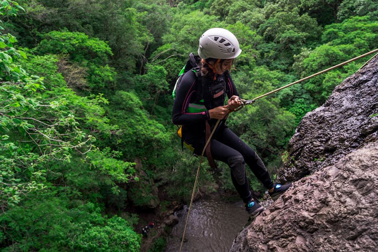 Woman Climbing A Mountain Cliff