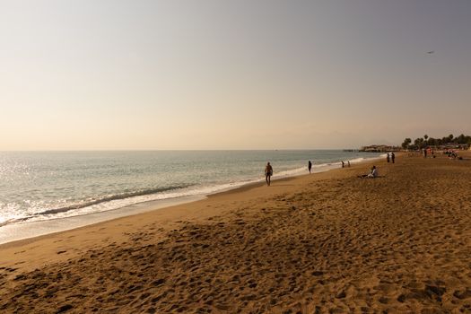 A serene beach scene with people enjoying a warm day by the shore, perfect for travel and lifestyle themes.