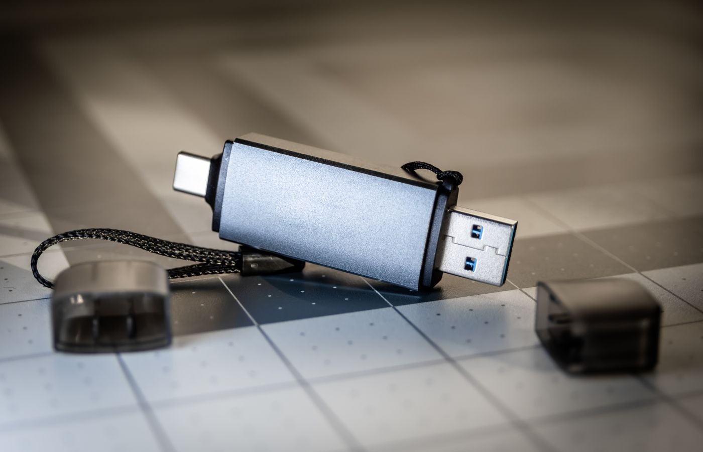 High-quality close-up of a dual USB-C and USB-A flash drive on a sleek grid-patterned background.