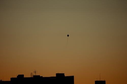 Silhouette of a Flying Kite Over the Buildings
