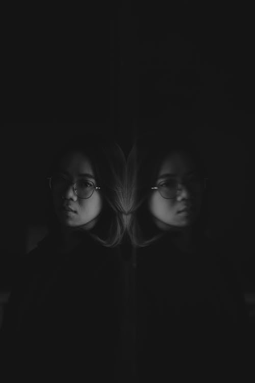 Free 

A Grayscale of a Woman in Eyeglasses Leaning on a Mirror Stock Photo