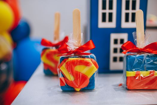 Superman-themed square lollipops with red bow, perfect for birthday celebrations.