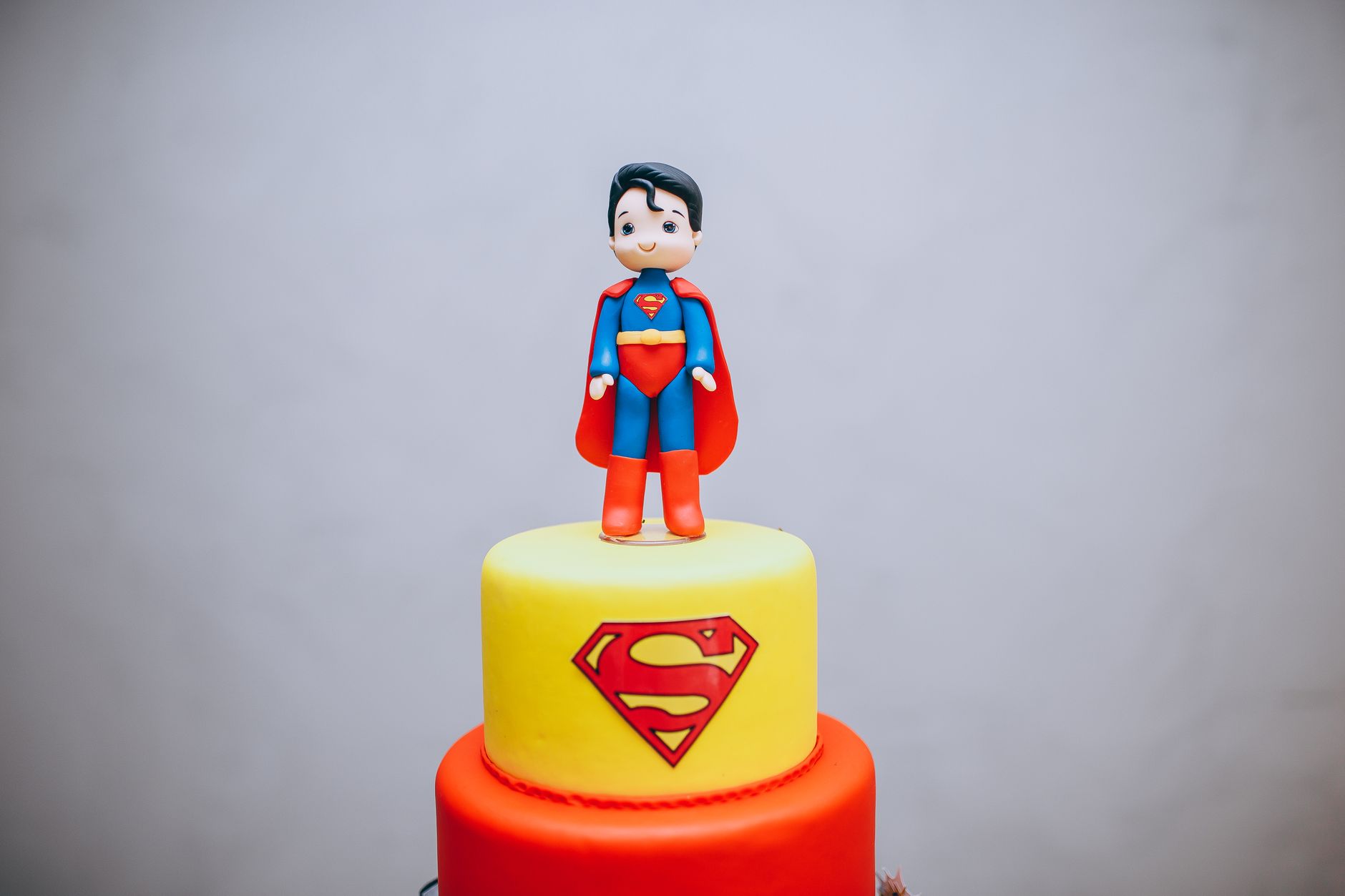 Colorful superhero cake featuring a fondant Superman figurine on top, perfect for themed parties.