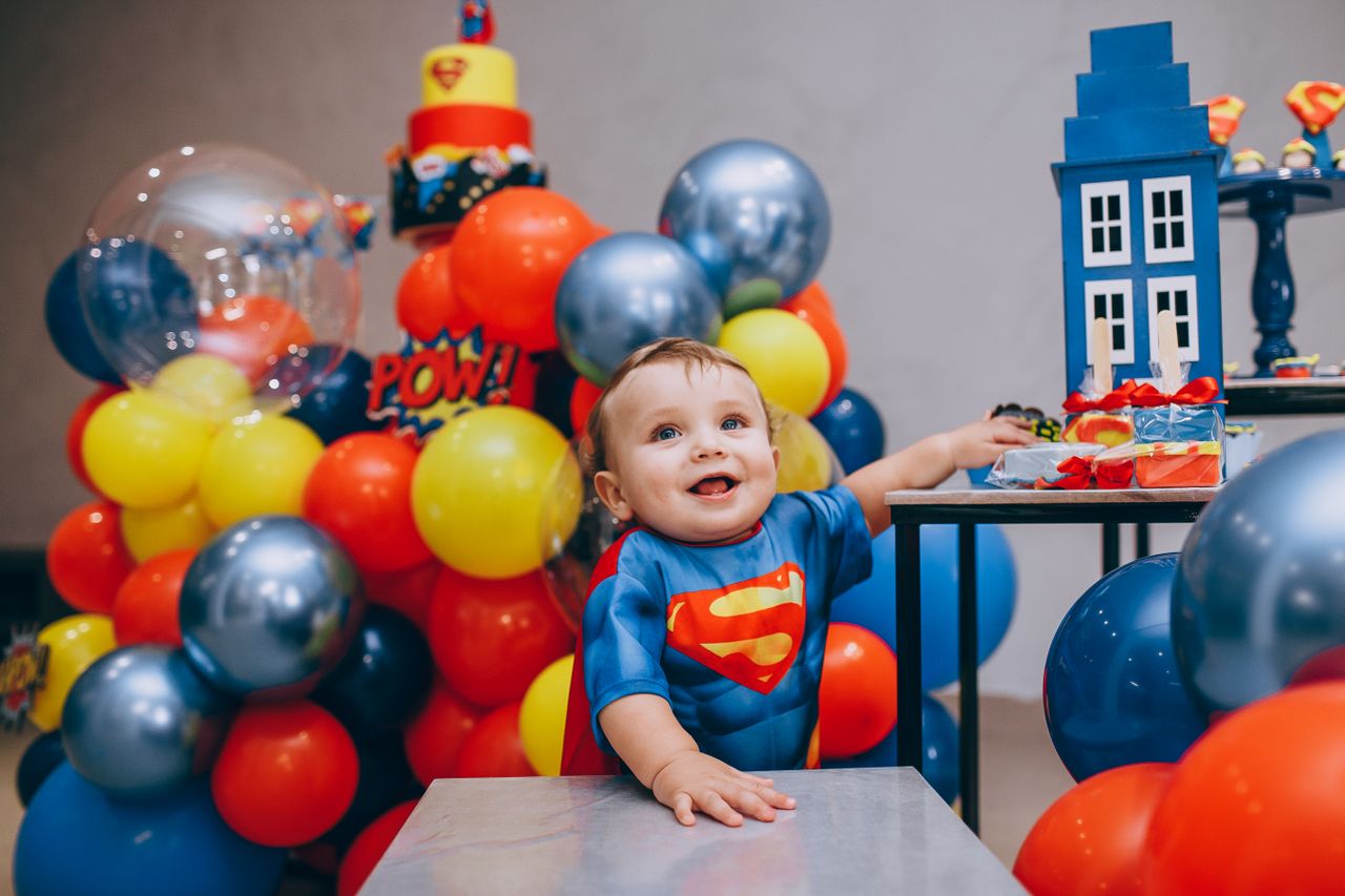 adorable baby in superhero costume celebrating a colorful birthday sur