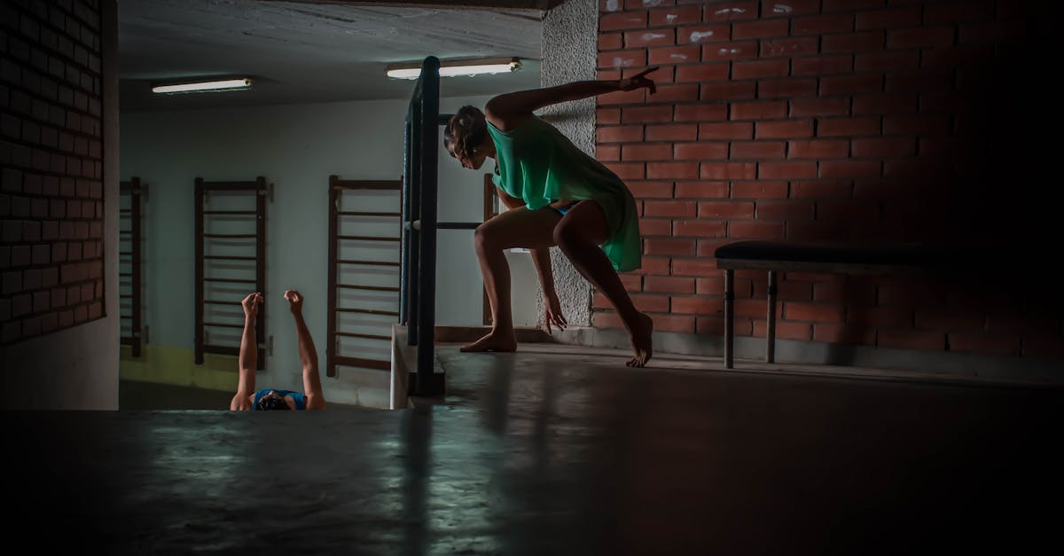 A woman dances expressively indoors with dramatic lighting against a brick wall in Santa Cruz, Bolivia.