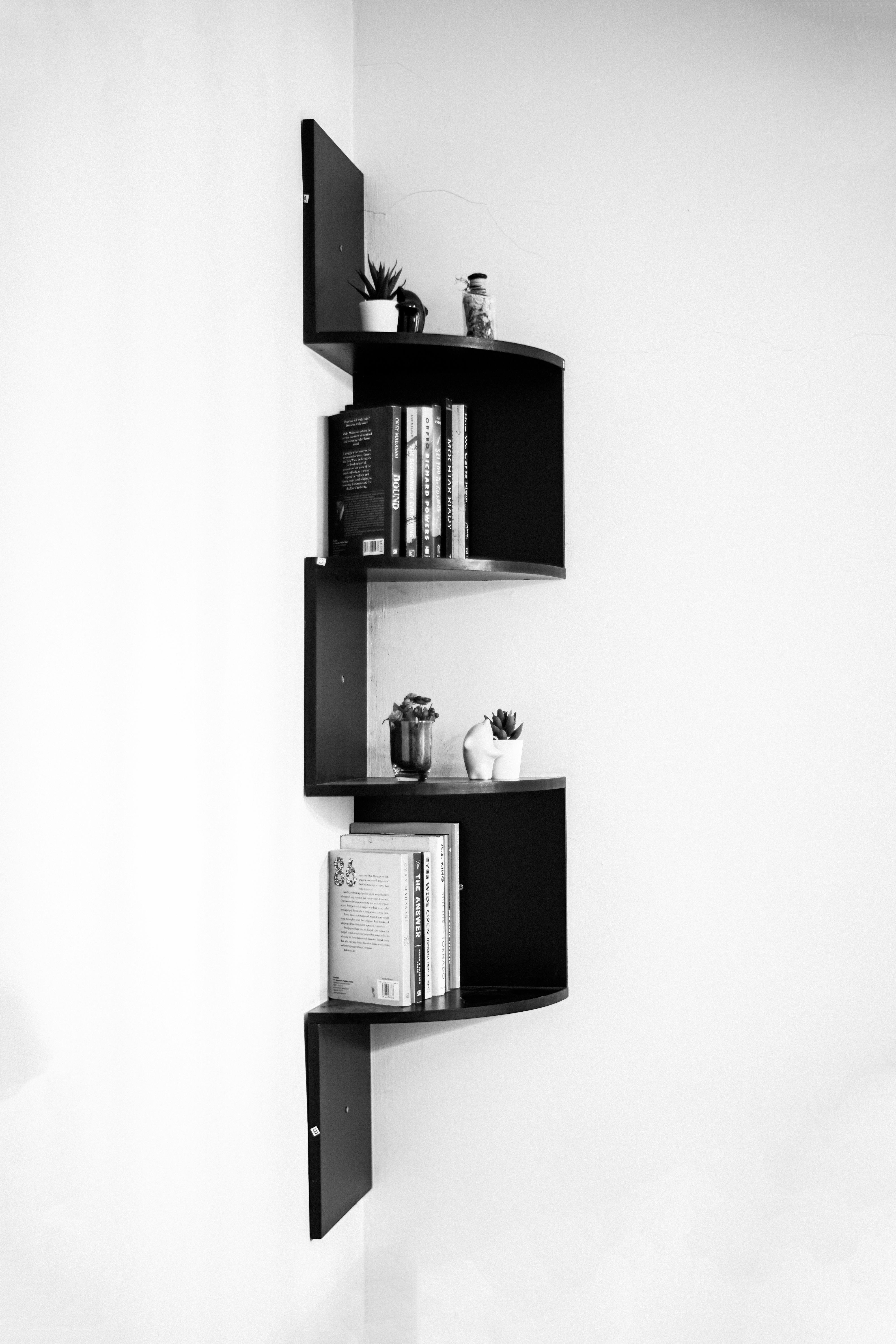 Free Elegant black corner shelf with books and decor in monochrome setting. Stock Photo