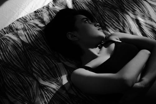 
A Grayscale of a Woman in a Tank Top Lying Down