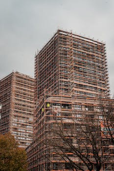 High-rise buildings under construction with extensive scaffolding in an urban setting.