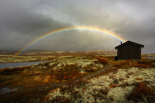 Free Scenic view of a cabin in Innlandet, Norway illuminated by a rainbow. Stock Photo