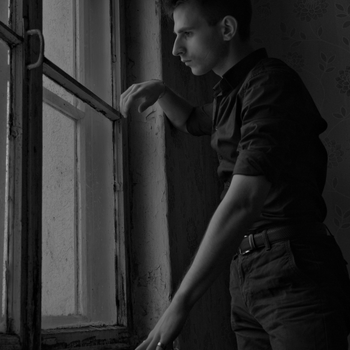 Thoughtful man gazing out window in monochrome.