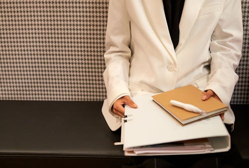 Woman in White Suit Holding Folder of Documents