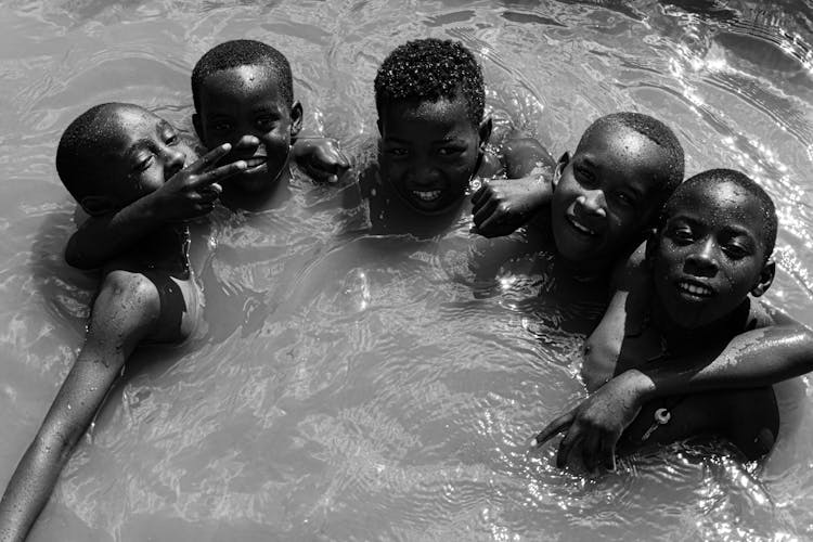 Grayscale Photo Of Young Boys Swimming Together
