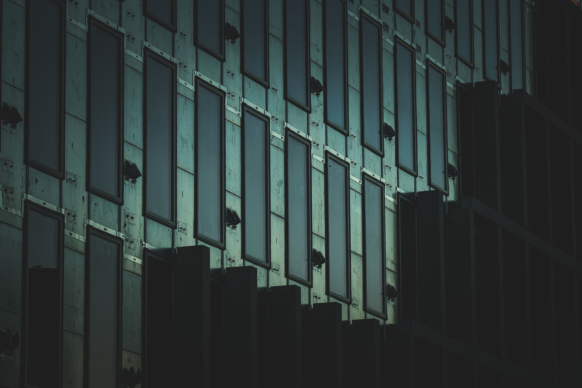 A dark building facade with a repeating geometric window pattern