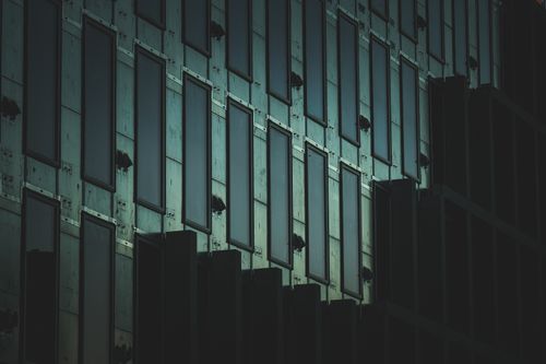Free Dark abstract facade of a modern building with geometric patterns and reflective windows. Stock Photo
