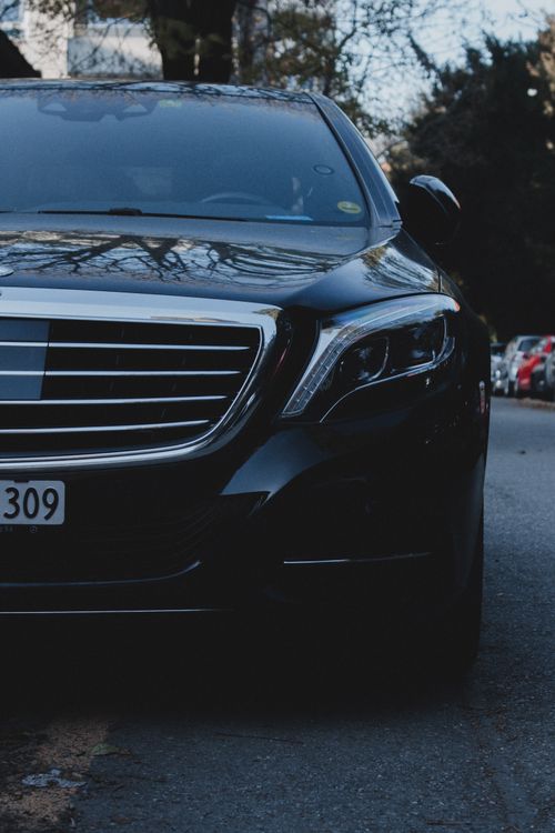 Free Close-up of a shiny black luxury car with distinctive grille parked on a city street, showcasing elegance and style. Stock Photo
