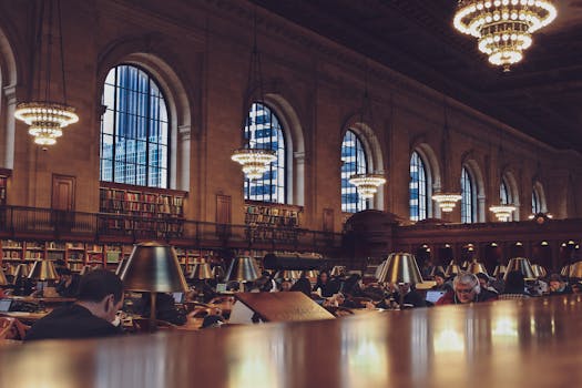 Interior view of a bustling reading room with chandeliers at the New York Public Library.