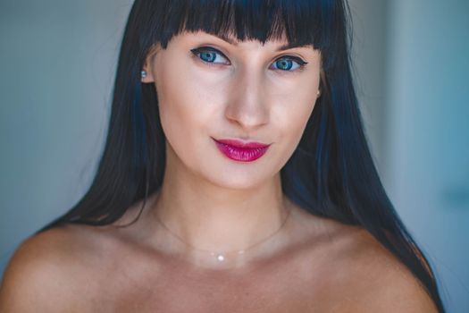 Close-up portrait of a woman with striking blue eyes and bold lipstick, showcasing elegance.