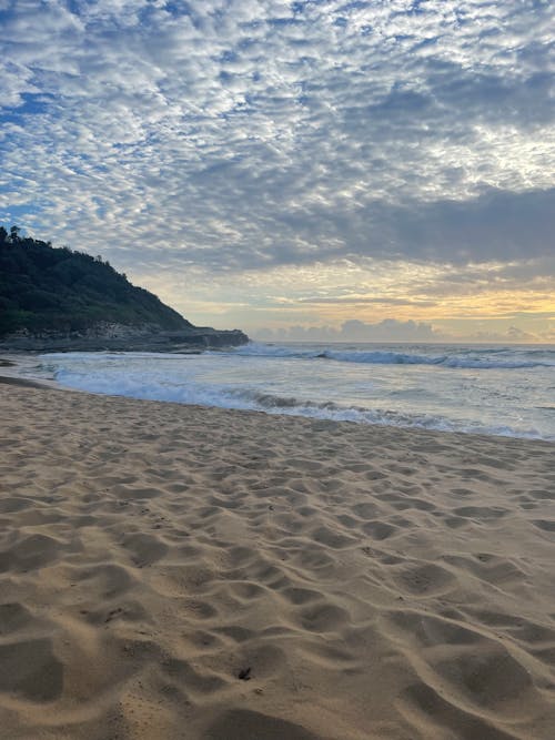 Sea Waves Crashing on Shore Under a Cloudy Sky