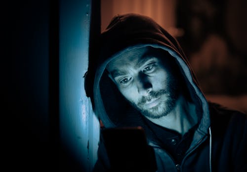 Man in Black Hoodie using a Smartphone