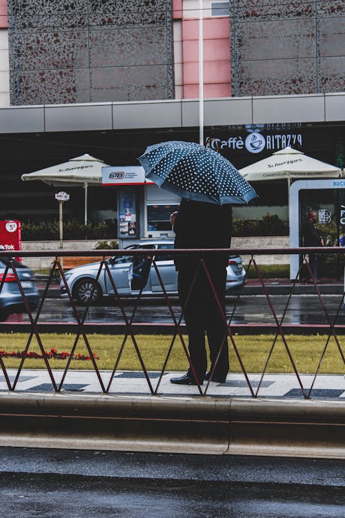 Person Standing on Sidewalk Holding an Umbrella