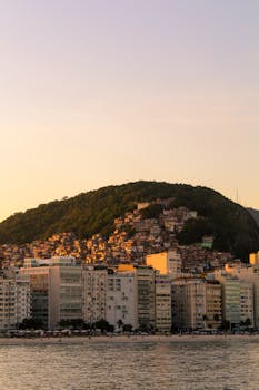 Beautiful cityscape of Rio de Janeiro at sunset featuring the beach and hillside buildings.