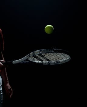 Close-up of a tennis racket and ball in motion on a dark background, capturing the energy of the sport.