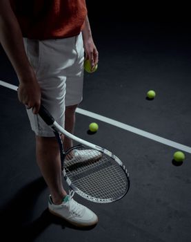 A close-up of a tennis player holding a racket and ball on an indoor court.