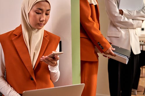 Free Portrait of Woman in Orange Jacket Holding Smartphone Stock Photo