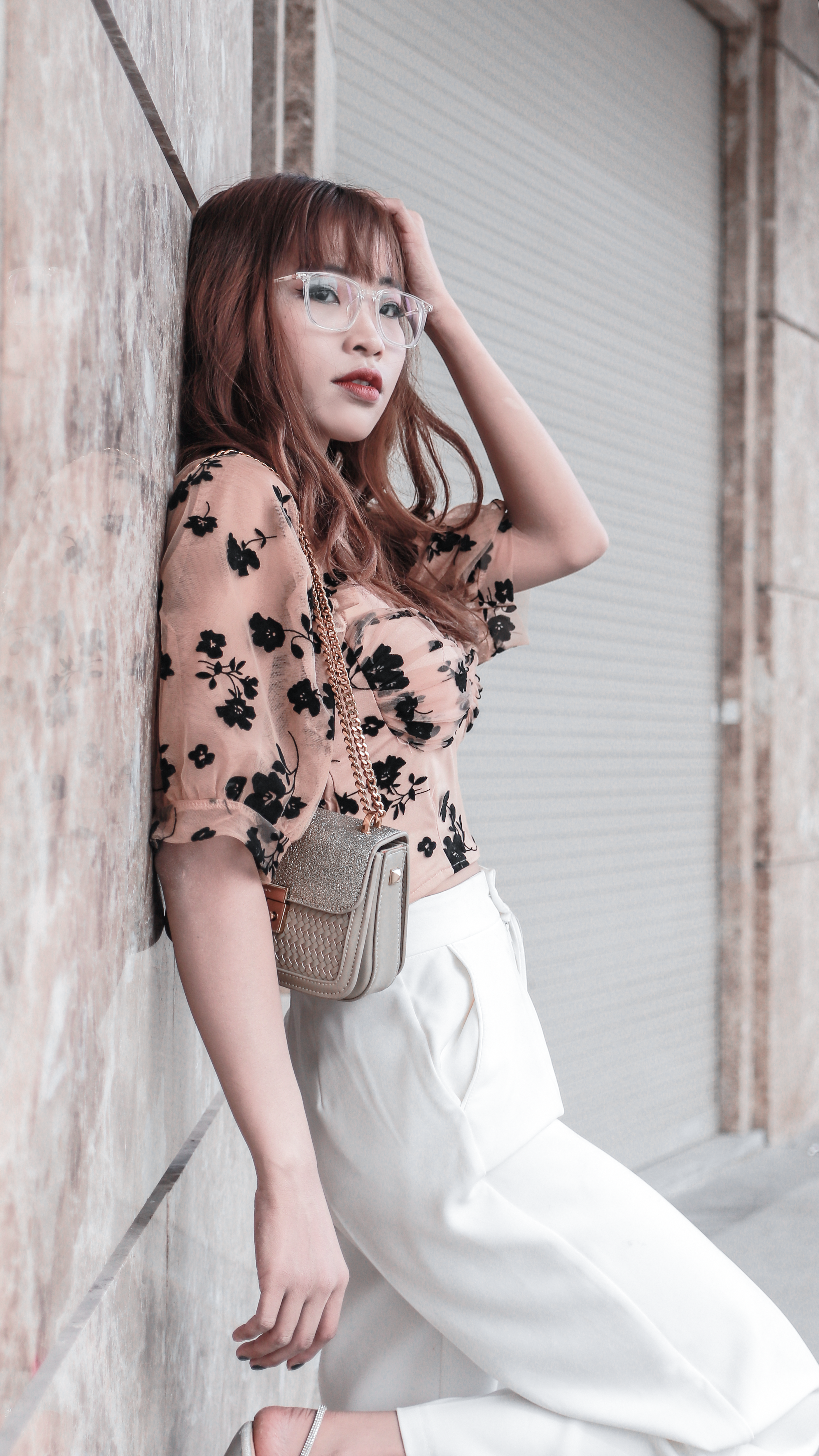 Fashionable Asian woman leaning against a wall in Hồ Chí Minh City, showcasing modern style.