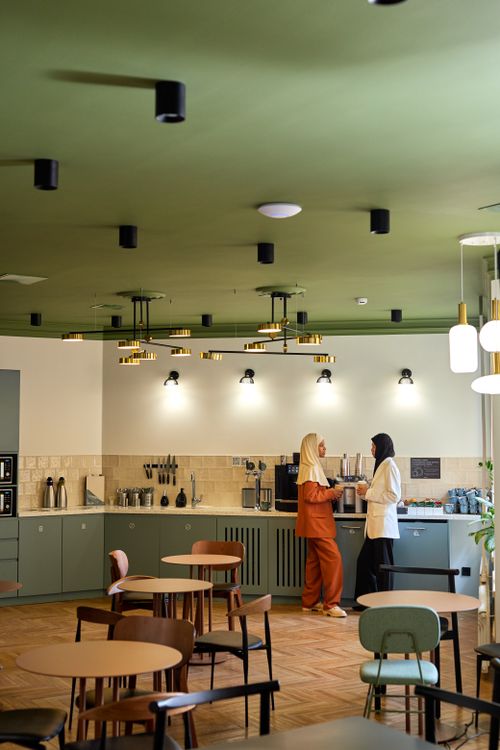 Free Two women conversing in a contemporary office kitchen with modern decor and furniture. Stock Photo
