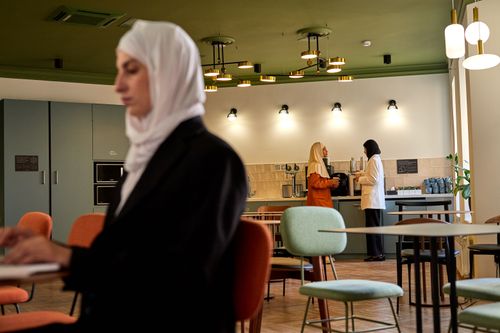Free Women collaborating in a contemporary office breakroom, creating a professional atmosphere. Stock Photo