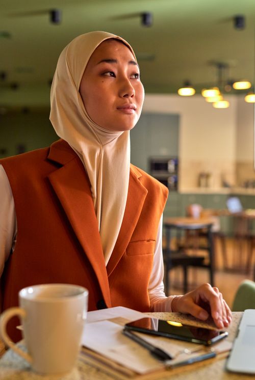 Free Confident woman in hijab working on a laptop in a cafe, sipping coffee. Stock Photo