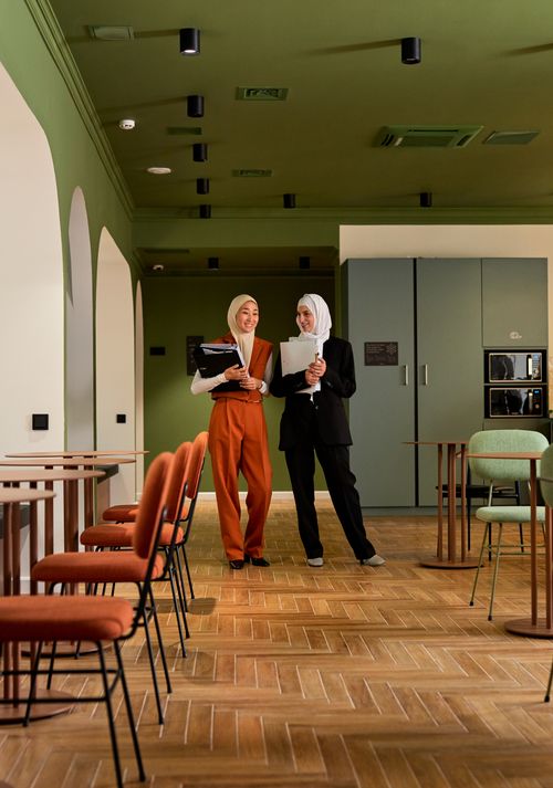 Free Two businesswomen in hijabs discussing work in a stylish office space with modern decor. Stock Photo