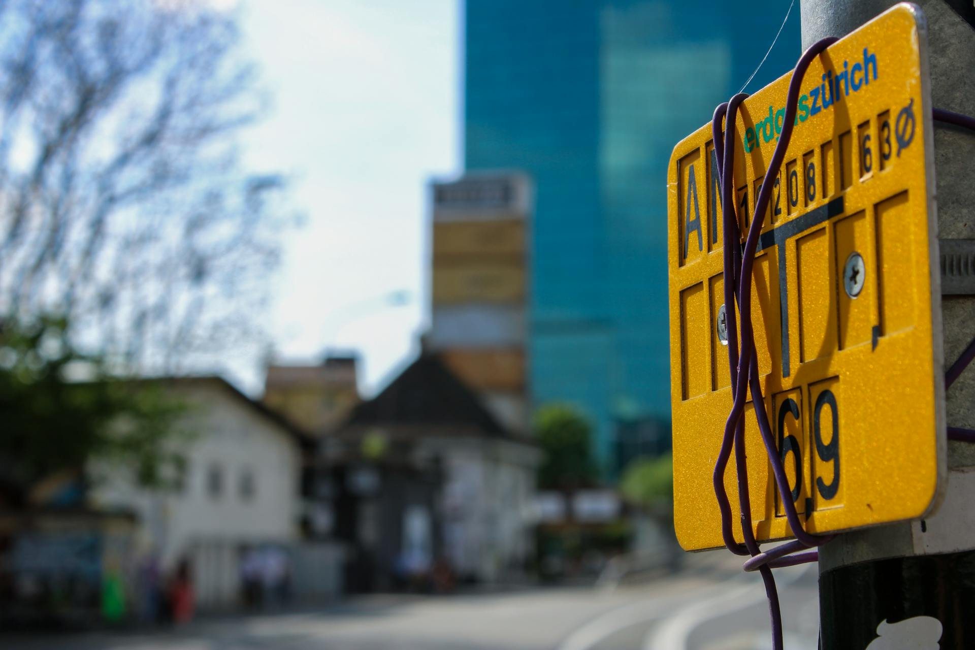 Close-up of a street sign in Zürich with blurred urban background, showcasing city life.