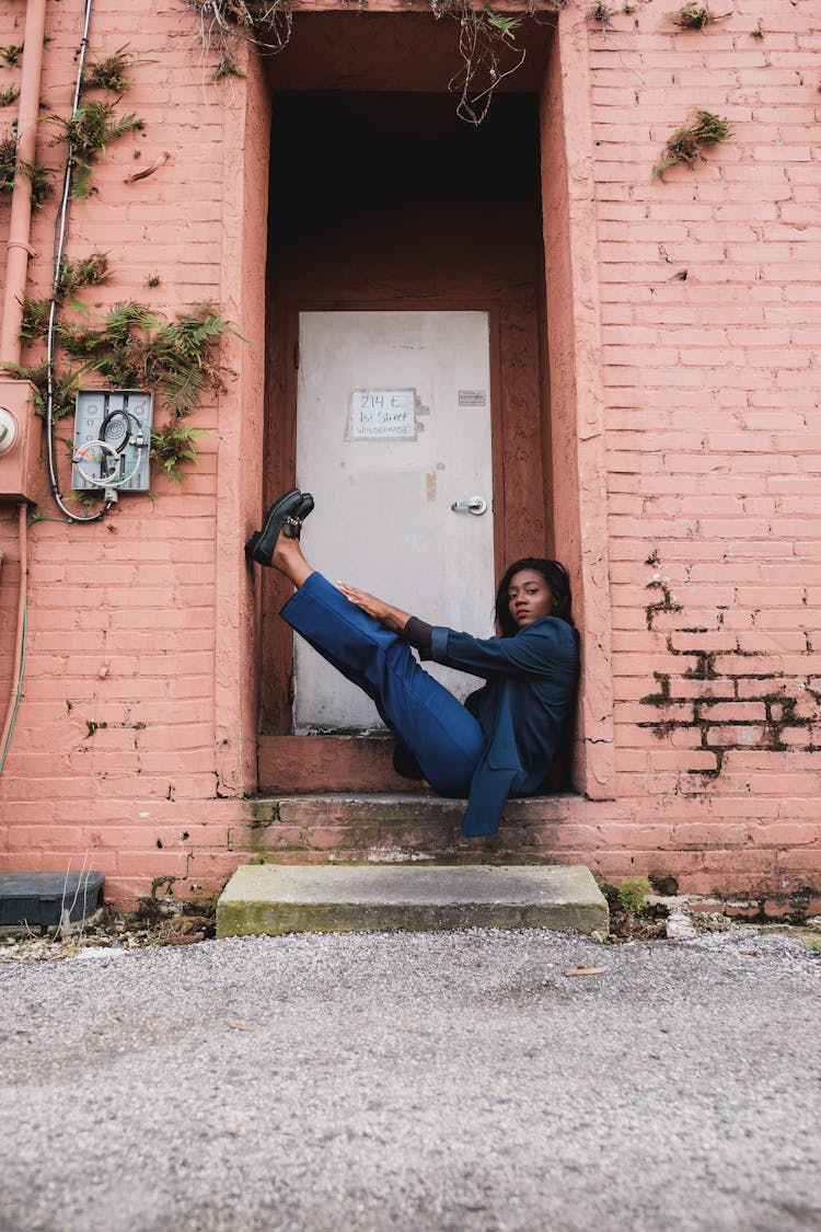 A Woman Sitting With Legs Up Between A Doorway