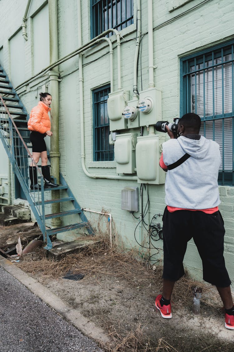 Photographer Taking Photo Of Woman Standing On Fire Escape