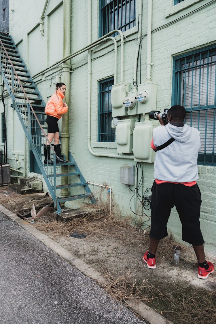 Man Photographing Woman Posing On Fire Escape