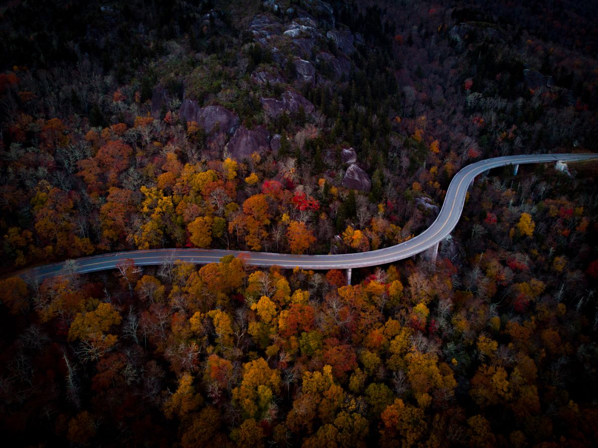 Aerial view of a mountain road curving through autumn forest near Boone, North Carolina, in the Blue Ridge, for people moving from the Northeast to the Carolinas