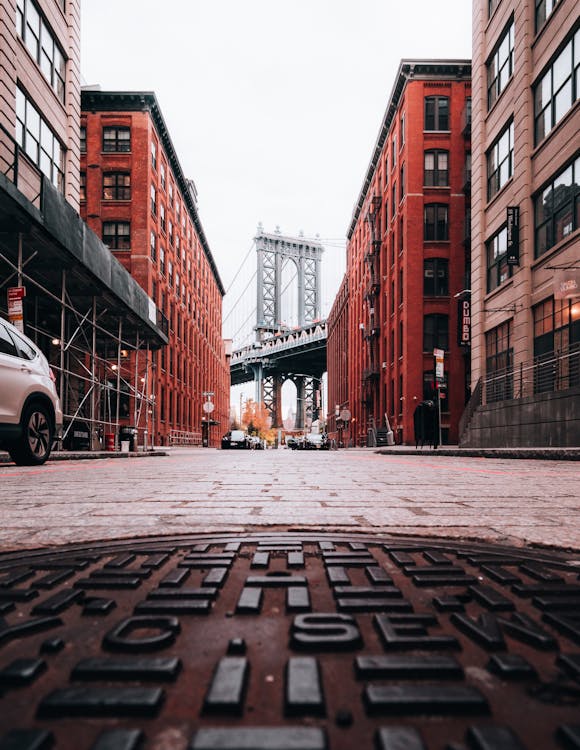 Free Ground level view of the Manhattan Bridge framed by red brick buildings in Brooklyn. Stock Photo