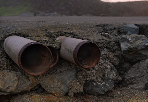 Free Steel Pipes Near Rocky Edge of the Road Stock Photo