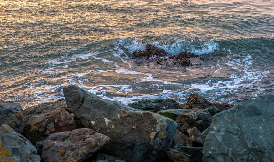 Waves breaking over rocks at sunset — photo by David McElwee on Pexels