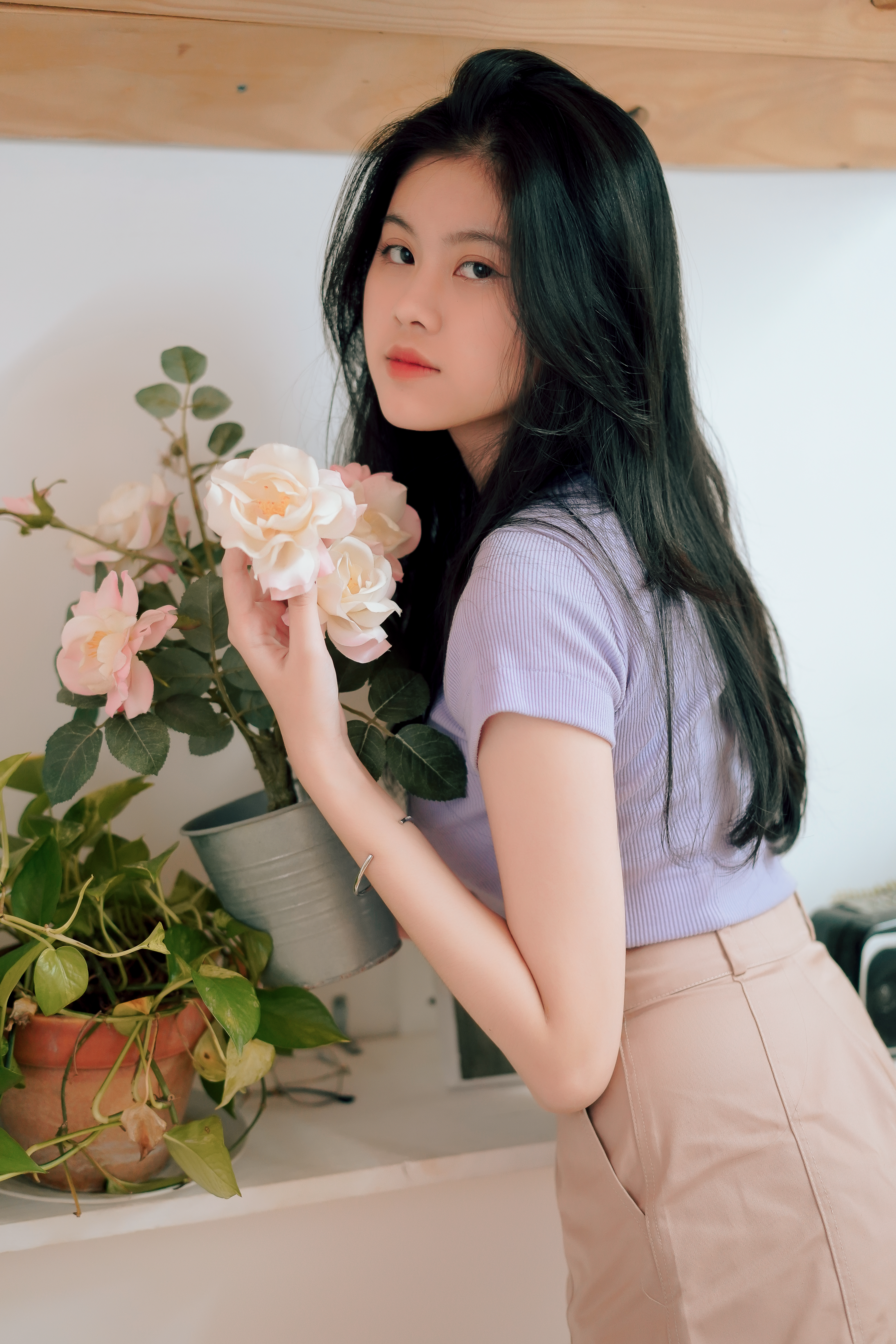 Graceful woman posing with roses indoors, blending elegance and nature.