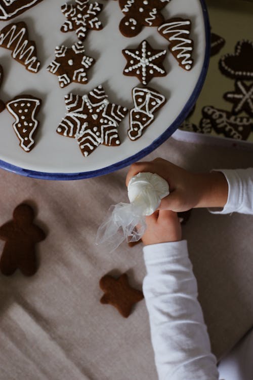 Hands of a Person Holding an Icing Bag Near Chocolate Cookies