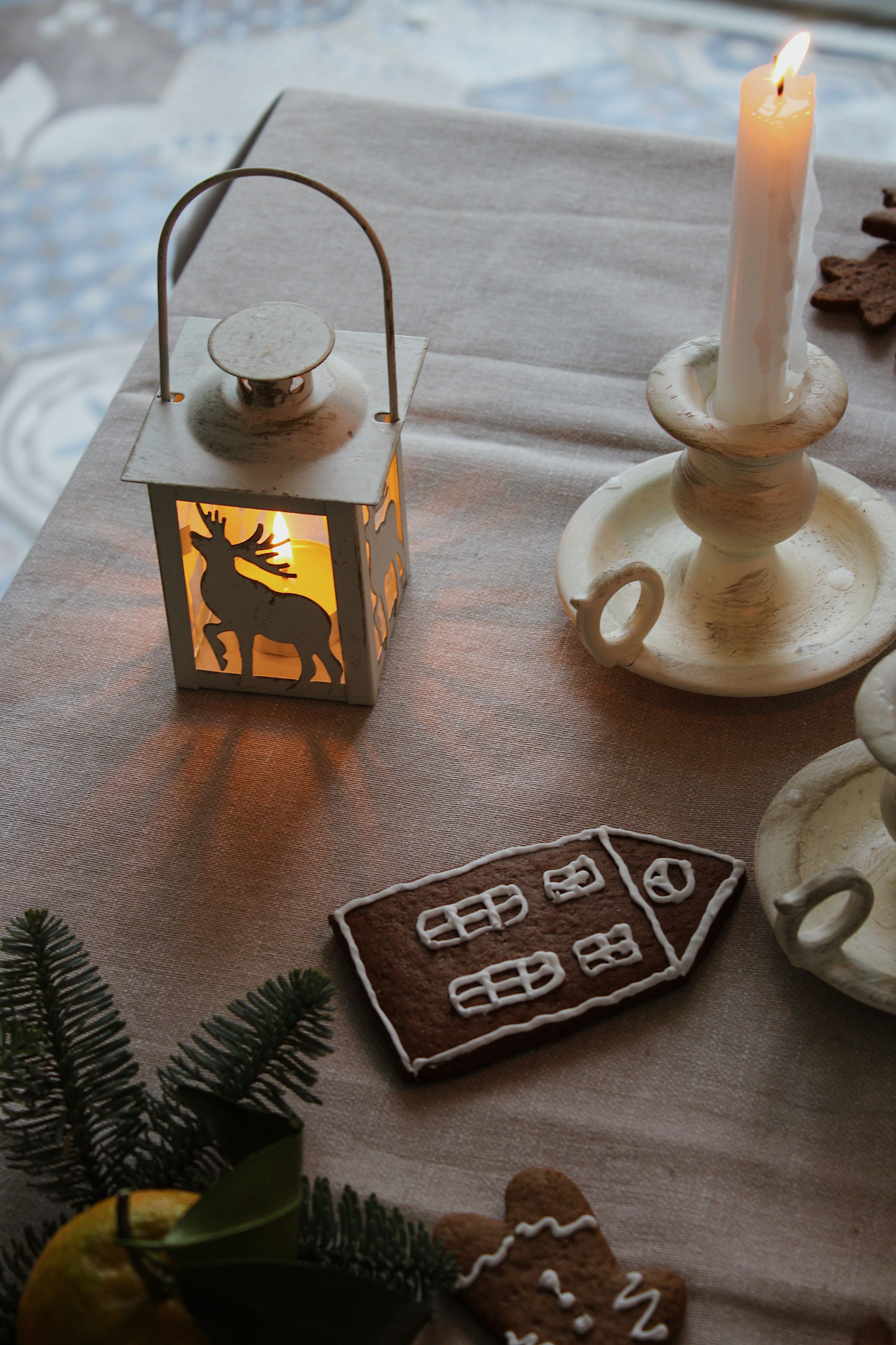 A festive table setting with a candle, gingerbread, and Christmas decor.