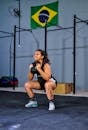 Woman in Black Sports Bra and Shorts Sitting on Brown Wooden Bench